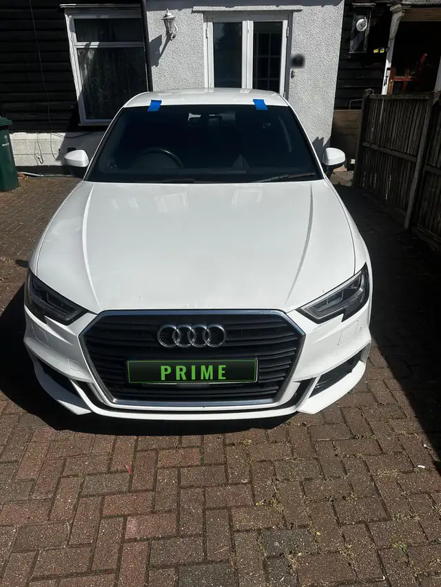 White Audi A3 on a block paved drive in Finchley with blue tape holding the new windscreen while it sets