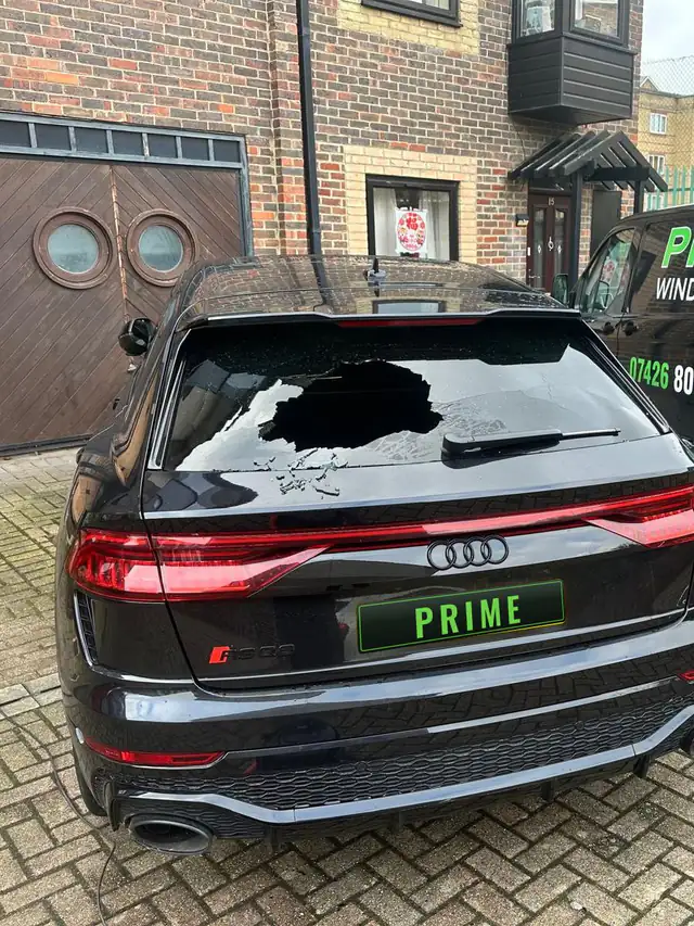 Black Audi RS Q8 with a smashed rear screen in an Edgware courtyard, the Prime Windscreens van parked alongside