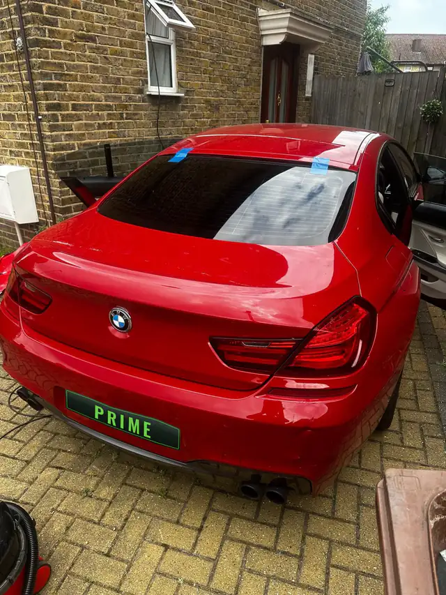 Red BMW 6 Series on a block paved drive in Cricklewood with its new rear screen taped in place