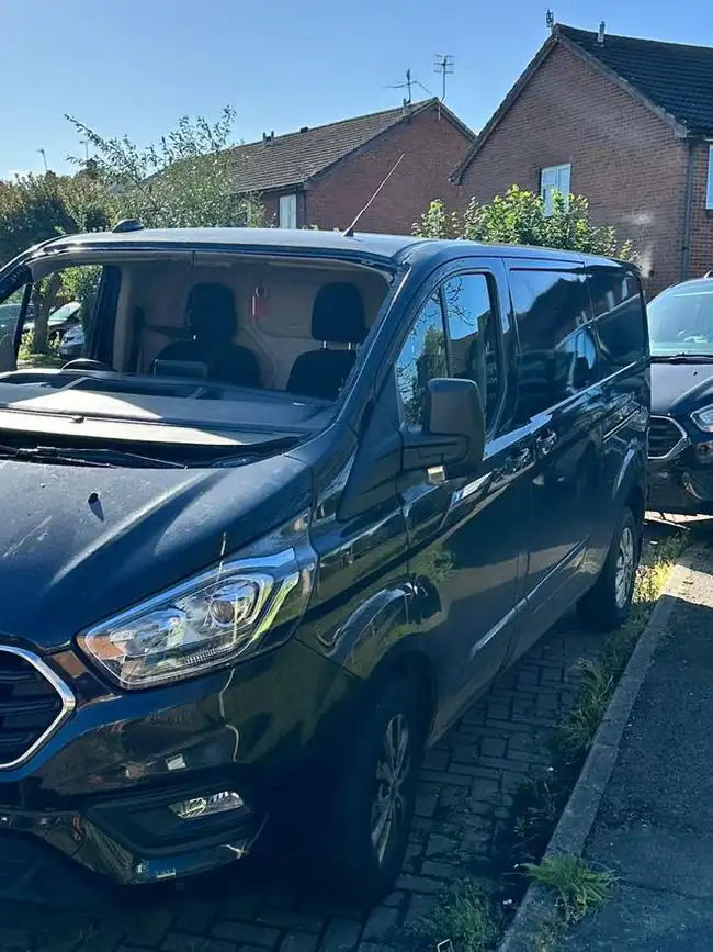 Before: dark blue Ford Transit Custom on a residential street with its windscreen taken out, the seats and dashboard in view