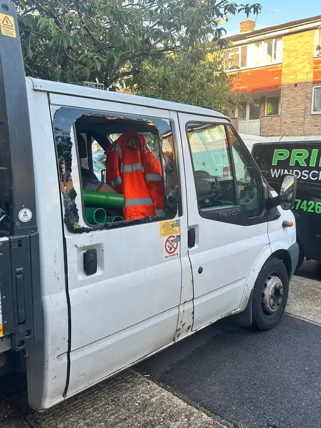 White Ford Transit tipper in Barking with a smashed rear side window, the Prime Windscreens van parked in front