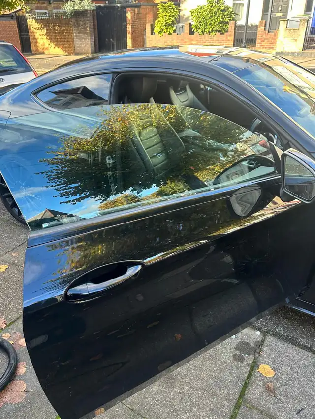 The same black Mercedes C Class coupe with its new frameless door window fitted and trees reflected in the glass