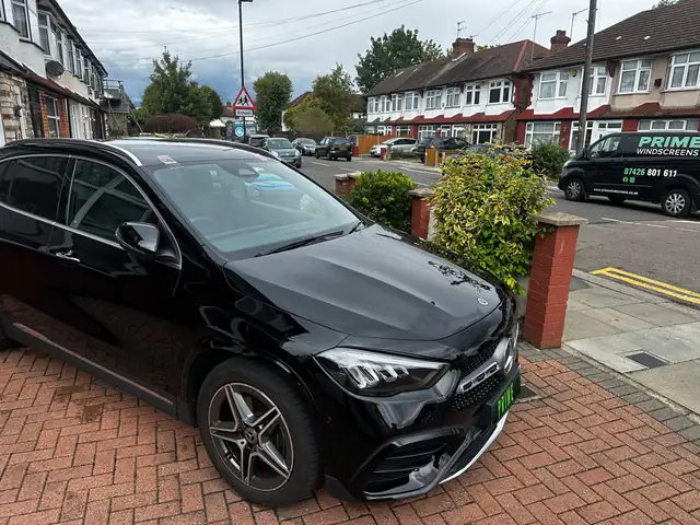 Black Mercedes GLA on a front driveway with a new windscreen and the Prime Windscreens van parked across the road