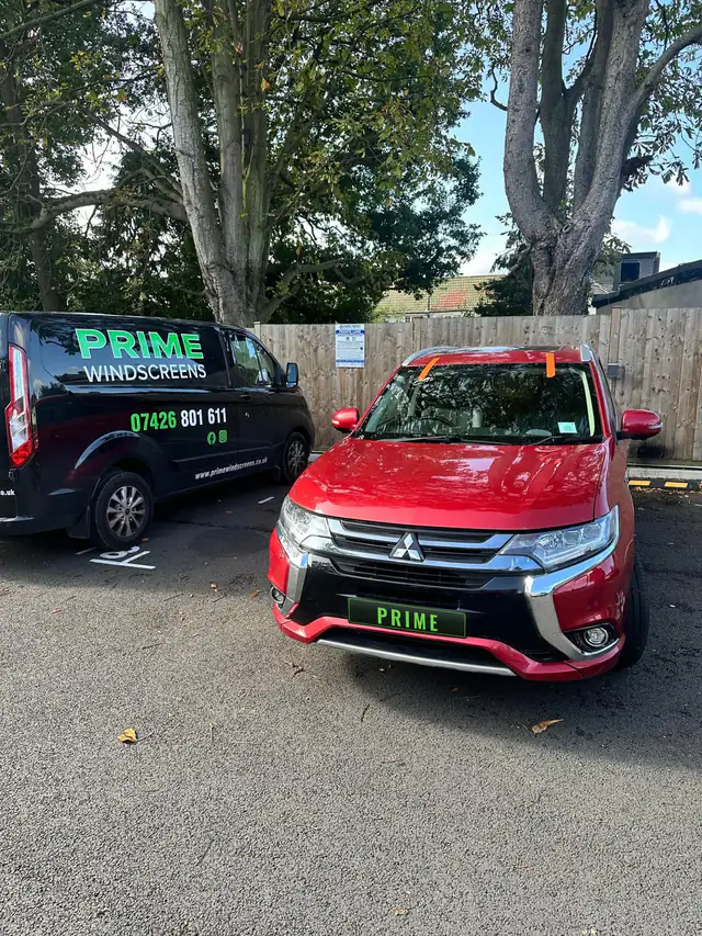 Red Mitsubishi Outlander in an Edgware car park with its new windscreen taped in place while the bond sets