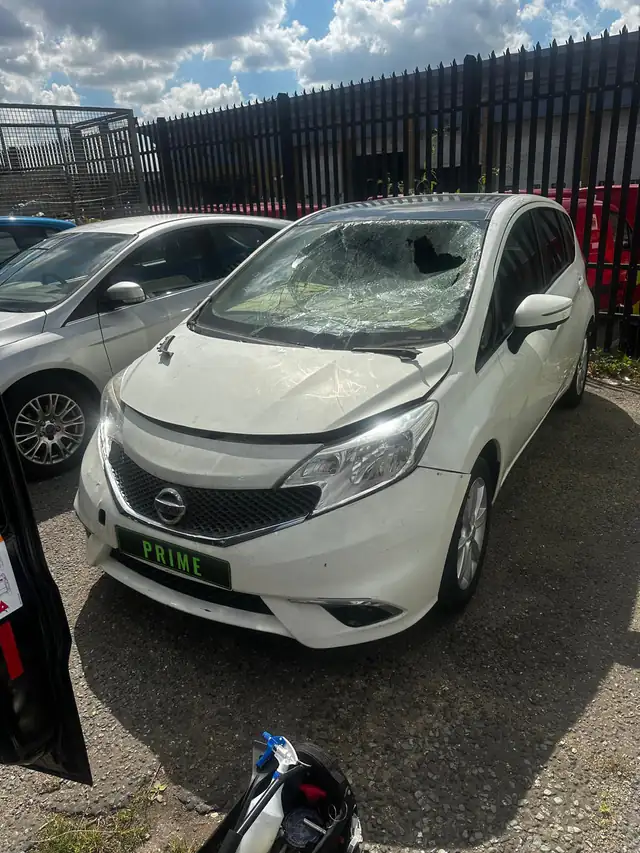 White Nissan Note in a fenced yard in Barking with its windscreen smashed, before the replacement