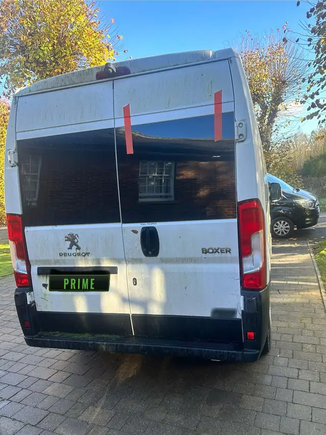 White Peugeot Boxer high roof van on a block paved drive with new glass in its right hand rear door, held by red tape