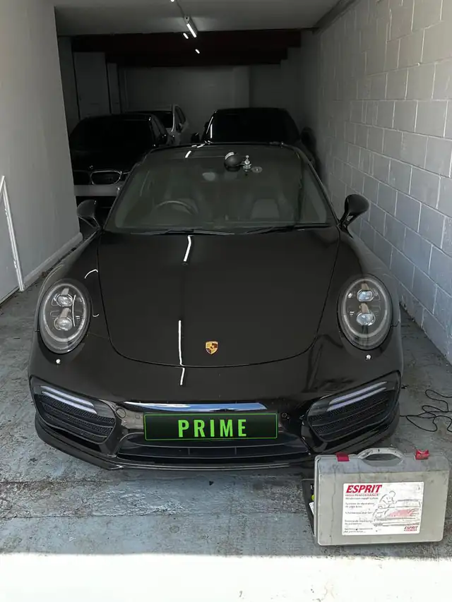 Stone chip repair on a black Porsche 911 Turbo in a private garage in Barnet, with the resin repair kit beside the car