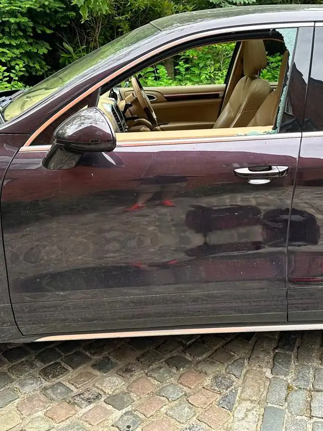 Before: dark brown Porsche Cayenne on a cobbled drive with its front passenger window broken out and pieces of glass left along the frame