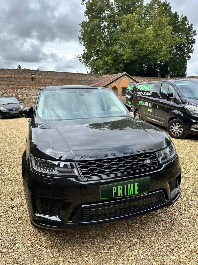 Black Range Rover Sport on a gravel drive in Barnet with a new windscreen, the Prime Windscreens van parked alongside