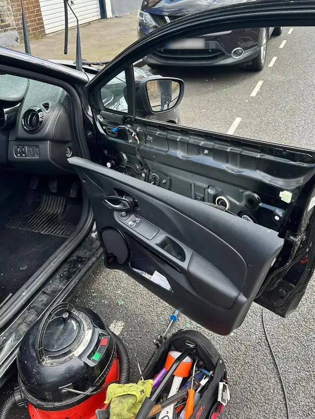 Black Renault Clio with the driver's door panel taken off to clear out the broken glass