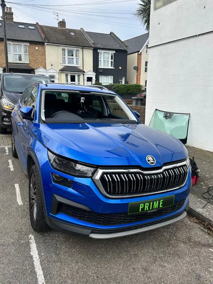 Before: blue Skoda Kodiaq in a parking bay on an N22 street with the old windscreen taken out and leaning against a wall