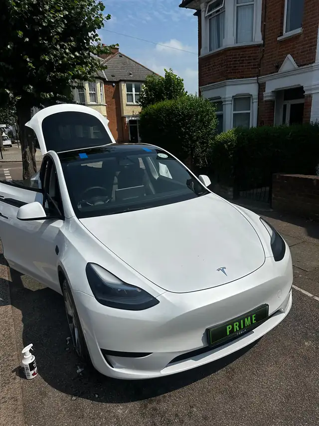 White Tesla Model Y outside a house in Cricklewood with blue tape holding its new windscreen