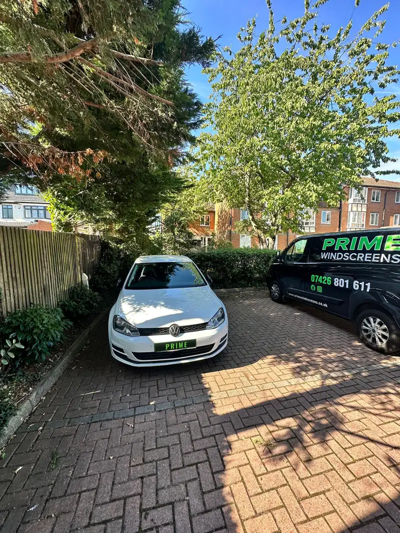 White Volkswagen Golf in a block paved parking court in Finchley, with the Prime Windscreens van alongside for a mobile windscreen job